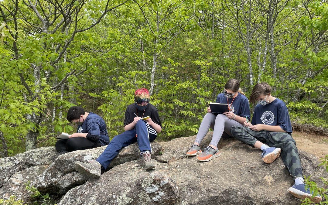 Four Trekkers students journal on a boulder after a hike