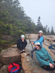 Students pose smiling while rock climbing