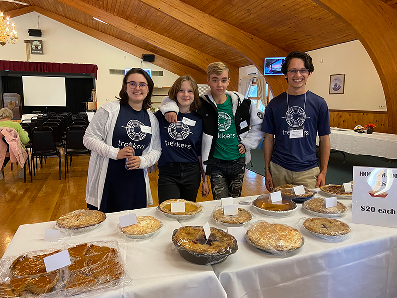 Four students, one adult pose at an auction table.