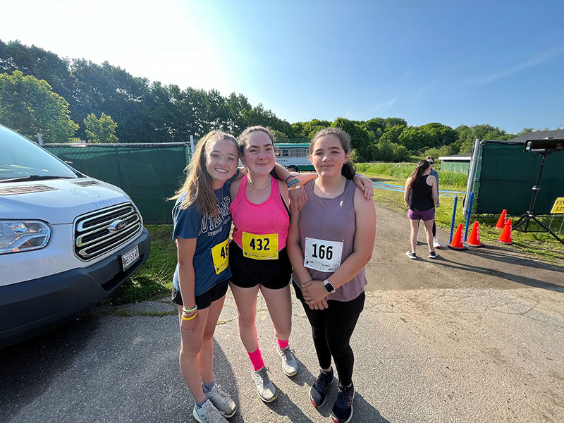 Three students pose outside in running gear.