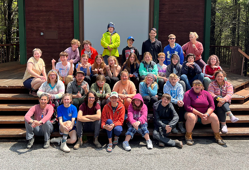 A group of students and adult volunteers pose smiling